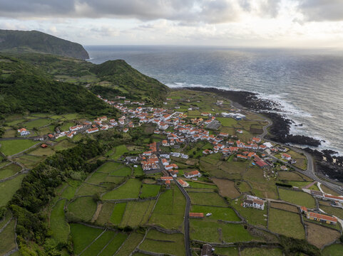 Aerial view of the coastal village of Faja Grande nestled among lush green fields, stone walls, and rugged cliffs along the Atlantic Ocean in Faja Grande, Azores, Portugal.