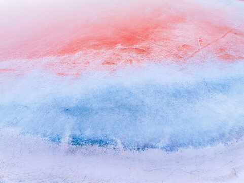 Aerial view of the vibrant red and blue textured surface of a salt flat with mineral deposits, Kos, Greece.