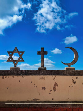 View of the Star of David, a Christian cross, and a crescent moon symbols representing religious harmony against a bright blue sky in San Marino.