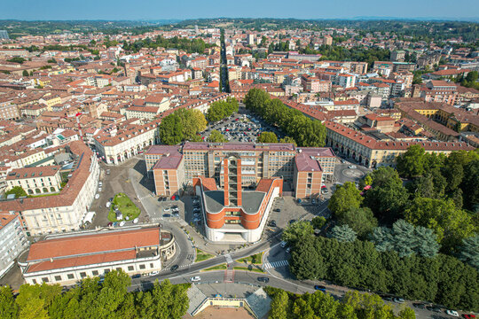 Aerial view of the Palazzo della Provincia di Asti with its distinctive tower and modern architecture amidst historic urban rooftops, tree-lined streets, and parks of Asti, Piedmont, Italy.