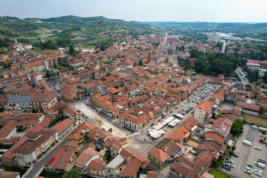 Aerial view of the historic town of Canale with its terracotta rooftops, a central square with market stalls, and surrounding vineyards in Canale, Piedmont, Italy.