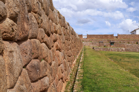 View of the ancient Inca stone wall with precise polygonal masonry at the Chinchero archaeological site under a blue sky in Cusco, Cusco, Peru.