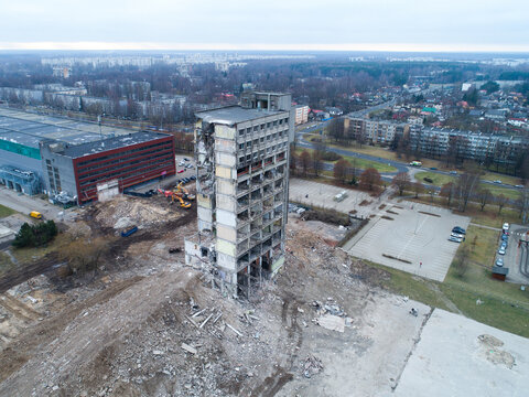 Riga, Latvia - 10 December 2017: Aerial view of a partially demolished high-rise building surrounded by construction debris and urban infrastructure.