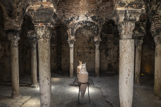 View of the ancient stone columns and arches inside the historic Arab Baths with terracotta amphorae on display in Palma, Balearic Islands, Spain.