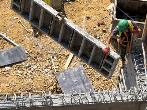 View of a construction worker in safety gear lifting a metal formwork panel at a building site in Istanbul, Istanbul, Turkiye.