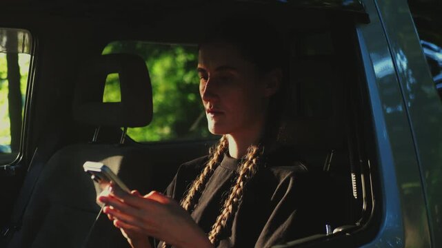 Woman using smartphone inside SUV, representing mobile automotive service, car booking app, connected travel, and digital mobility business.