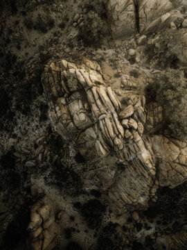 Aerial view of rugged desert rock formations and boulders with desert shrubs and sandy terrain in Nevada, United States.