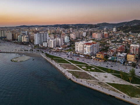 Aerial view of the coastal city of Vlora at sunset, featuring the urban skyline, modern apartment buildings, and the waterfront promenade in Vlora, Vlore County, Albania.