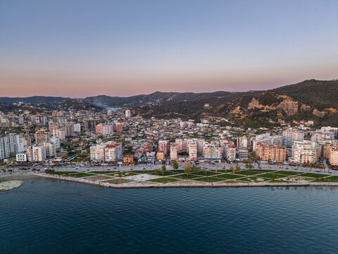 Aerial view of the coastal city of Vlora, featuring modern apartment buildings along the waterfront promenade, green park areas, and the calm sea in Vlora, Vlore County, Albania.