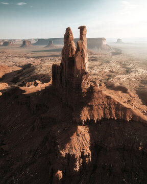 Aerial view of the Totem Pole rock formation in Monument Valley, with rugged sandstone spires and desert landscape under a clear sky in Oljato-Monument Valley, Arizona, United States.