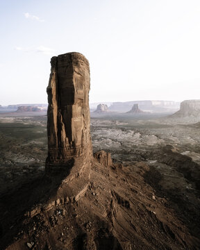 Aerial view of a towering red rock monolith in Monument Valley surrounded by a vast desert landscape in Oljato-Monument Valley, Arizona, United States.