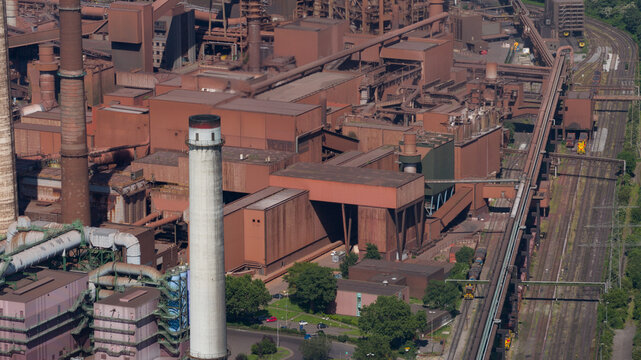 Aerial view of Kokerei Schwelgern coking plant at thyssenkrupp Steel site, featuring industrial chimneys, steel structures, and railway tracks in Duisburg, North Rhine-Westphalia, Germany.