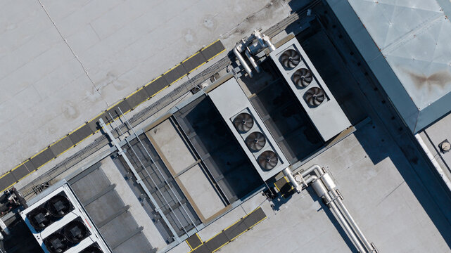 Aerial view of industrial rooftop HVAC cooling units with ventilation fans and metal piping systems in Nieuwegein, Utrecht, Netherlands.