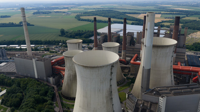 Aerial view of Kraftwerk Niederaussem power plant with its iconic cooling towers, industrial infrastructure, and surrounding green fields in Bergheim, Nordrhein-Westfalen, Germany.
