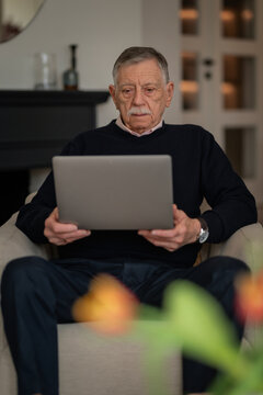 Senior man reading medical results on laptop at home