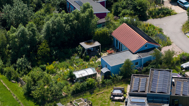 Aerial view of Ecodorp Bolderburen featuring sustainable houses with solar panels, lush gardens, and greenhouses surrounded by dense greenery in Almere, Flevoland, Netherlands.