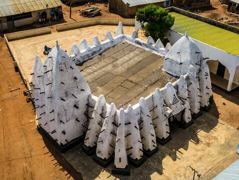 Aerial view of the historic Larabanga Mosque with its distinctive white Sudano-Sahelian architecture, wooden beams, and flat roof in Ghana.