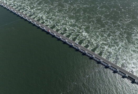 Aerial view of the Eastern Scheldt Storm Surge Barrier with turbulent water and road traffic in Vrouwenpolder, Zeeland, Netherlands.