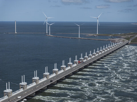 Aerial view of the Eastern Scheldt Storm Surge Barrier with wind turbines and turbulent water in Vrouwenpolder, Zeeland, Netherlands.