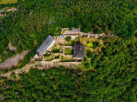 Aerial view of Tocnik Castle, a historic medieval fortress surrounded by dense green forests in the Bohemian landscape, Tocnik, Stredocesky kraj, Czechia.