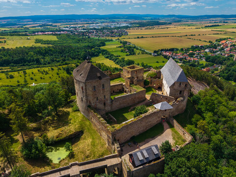 Aerial view of Tocnik Castle featuring stone walls, historic ruins, and surrounding lush green forests and fields in Tocnik, Stredocesky kraj, Czechia.