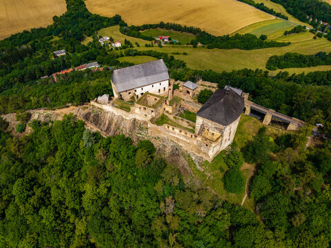 Aerial view of Tocnik Castle surrounded by dense forests and rolling agricultural fields in Tocnik, Stredocesky kraj, Czechia.