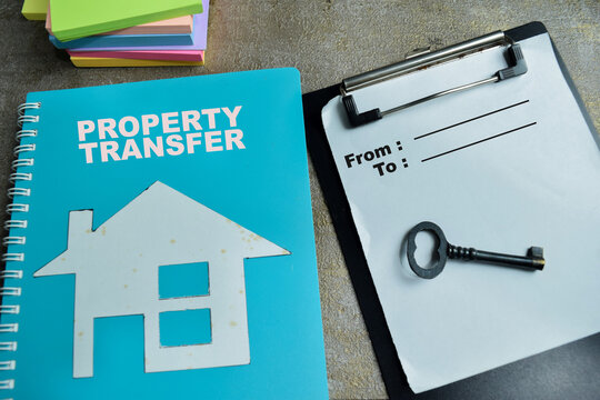 Concept of property transfer with key and ownership agreement write on clipboard isolated on Wooden Table. For real estate transaction
