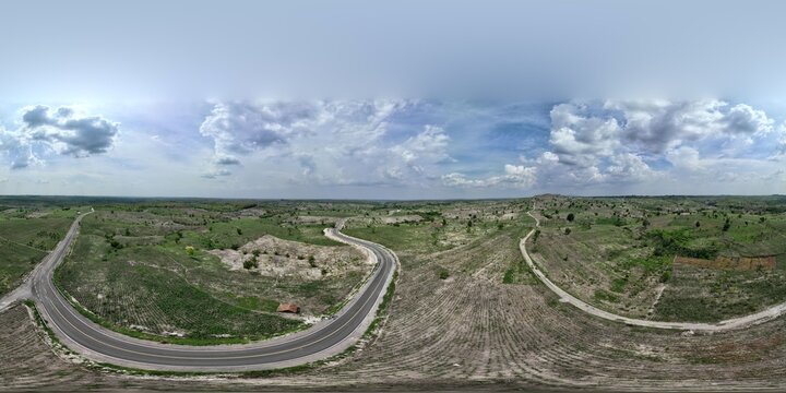 Aerial view of a winding road cutting through the rural hilly landscape of Bojonegoro, East Java, Indonesia.