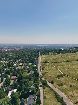 Aerial view of Chautauqua Park with its expansive grassy fields and trails adjacent to the residential neighborhoods and tree-lined streets of Boulder, Colorado, United States.