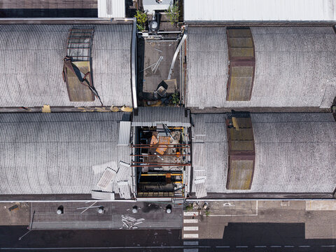 Aerial view of industrial warehouse rooftops with corrugated metal sheets and a central open section in Casale Monferrato, Piedmont, Italy.