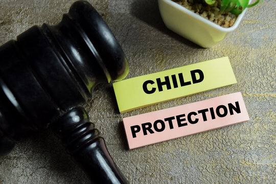 Concept of child protection write on sticky notes and judge gavel isolated on Wooden Table. For safety care insurance and family support