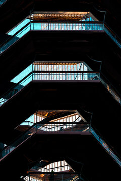 Architectural detail of the intricate steel structure of The Vessel in Hudson Yards, Manhattan, showing geometric stairs, balconies, and copper reflections in New York City.