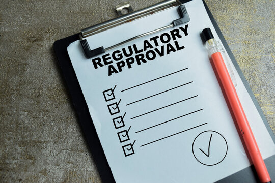 Concept of regulatory approval write on clipboard with compliance checklist isolated on Wooden Table. For standard requirement