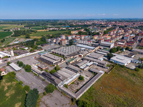 Aerial view of the industrial complex with warehouses and factory buildings on the outskirts of the town, surrounded by residential areas and fields in Casale Monferrato, Piedmont, Italy.