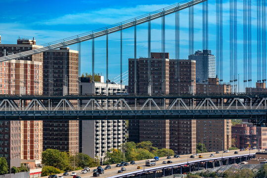 Scenic elevated view of brick apartment buildings along the FDR Drive highway with active traffic flowing beneath the impressive steel cable structure of the Manhattan Bridge, New York