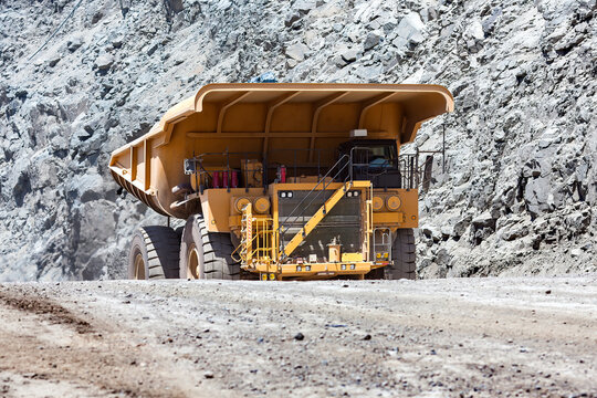 Large mining truck carrying heavy loads through an open pit copper mine in Chile, moving along a dusty road against steep rock formations.