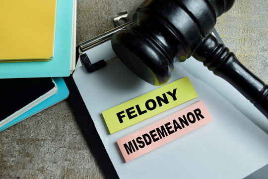 Concept of felony misdemeanor write on sticky notes and judge gavel isolated on Wooden Table. For criminal law justice court legal classification