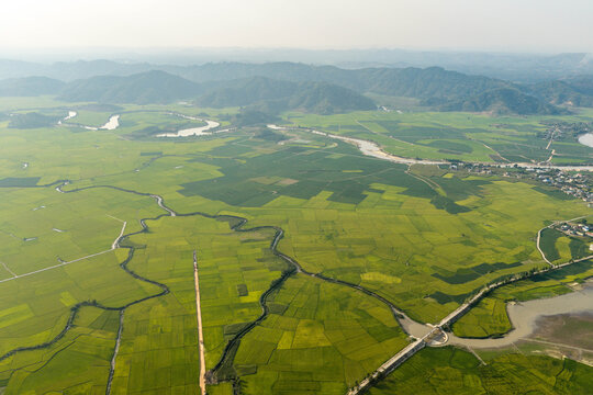 Aerial view of Lak Lake surrounded by lush green rice paddies and winding rivers in Lien Son Lak, Dak Lak, Vietnam.
