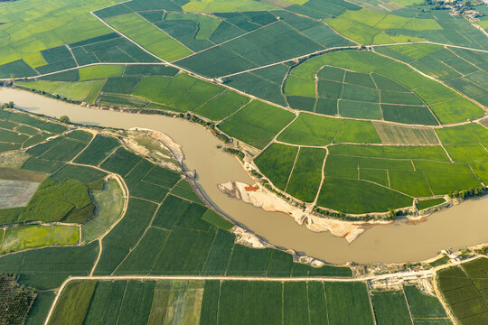 Aerial view of Lak Lake surrounded by vibrant green rice fields and a winding river in the rural landscape of Lien Son Lak, Dak Lak, Vietnam.