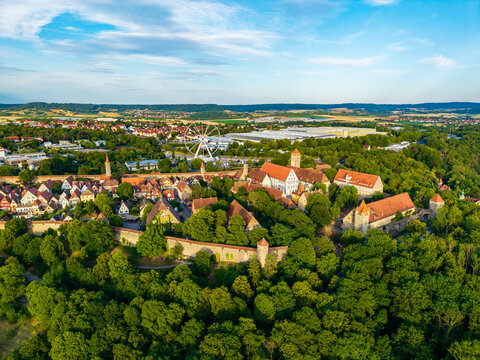 Aerial view of the historic medieval town of Rothenburg ob der Tauber with defensive walls, red-tiled rooftops, and a ferris wheel in Rothenburg ob der Tauber, Bavaria, Germany.