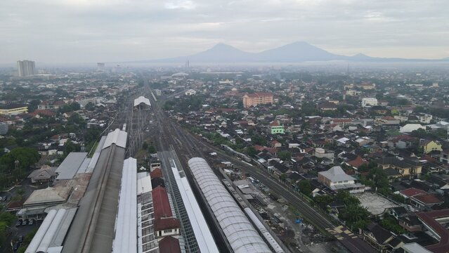 Aerial view of Stasiun Solo Balapan with its railway tracks, platforms, and surrounding urban landscape under a cloudy sky in Banjarsari, Central Java, Indonesia.