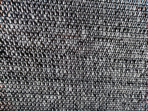 Black agricultural shade net texture background for greenhouse and garden protection featuring woven synthetic material pattern to filter sunlight for nursery plants and crops.