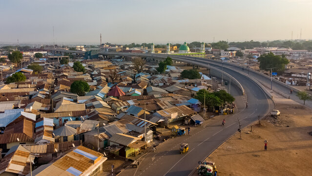 Aerial view of Tamale Interchange spanning over the residential area with metal rooftops and a mosque in the background in Tamale, Northern Region, Ghana.