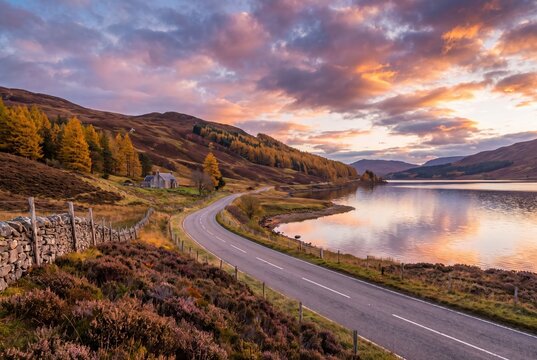 Scottish highlands road winding along loch at sunset autumn landscape