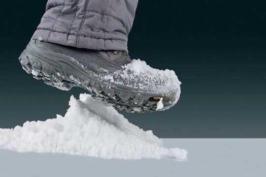 Navy blue winter boot stepping through crisp white snow with visible quilted fabric and lugged sole for cold weather and winter walking concepts
