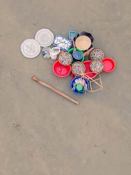 Aerial view of a person wearing a conical hat sorting fresh fish in colorful plastic basins and baskets on a flat surface in Vietnam.