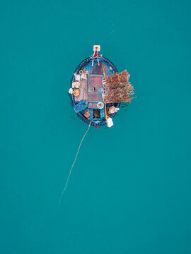 Aerial view of a traditional Vietnamese basket boat floating on calm turquoise water with fishing gear and nets on board in Vietnam.