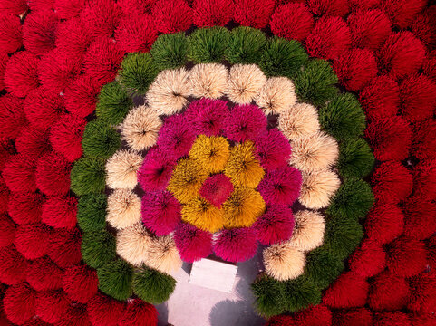 Aerial view of colorful incense sticks arranged in vibrant circular patterns of red, green, yellow, and pink, creating a striking geometric display in Vietnam.