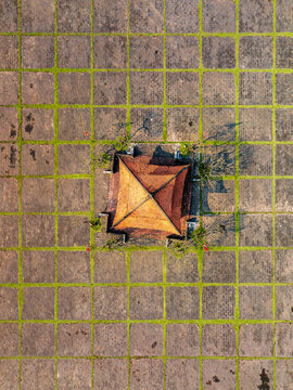 Aerial view of a traditional building with a terracotta roof centered in a geometric stone courtyard with grass-filled grid lines in Vietnam.