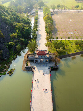Aerial view of the historic gate and stone bridge at Hoa Lu Ancient Capital surrounded by lush greenery and water in Vietnam.